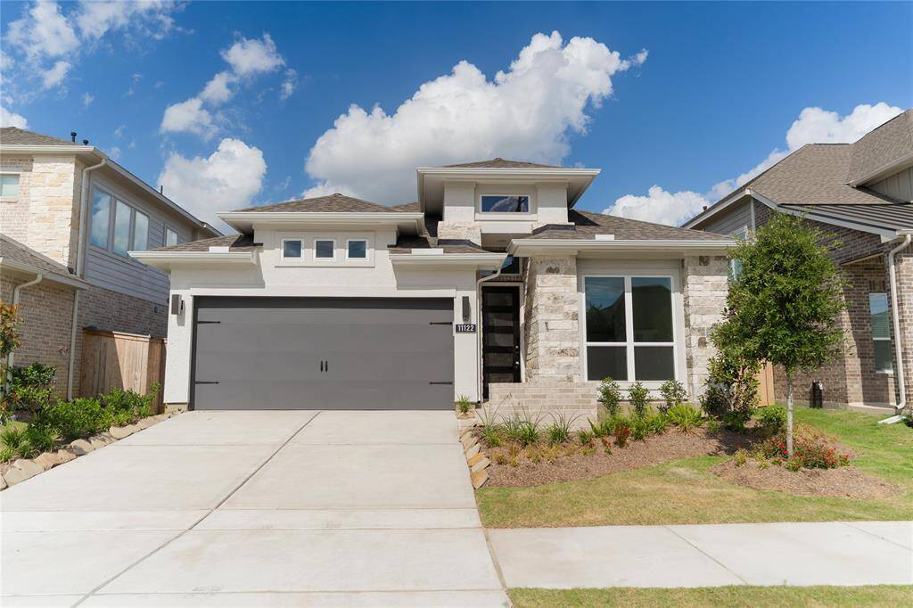 This modern home features a sleek exterior with a mix of stone and siding, a large two-car garage, and a well-maintained front yard. Its clean lines and contemporary design offer excellent curb appeal.