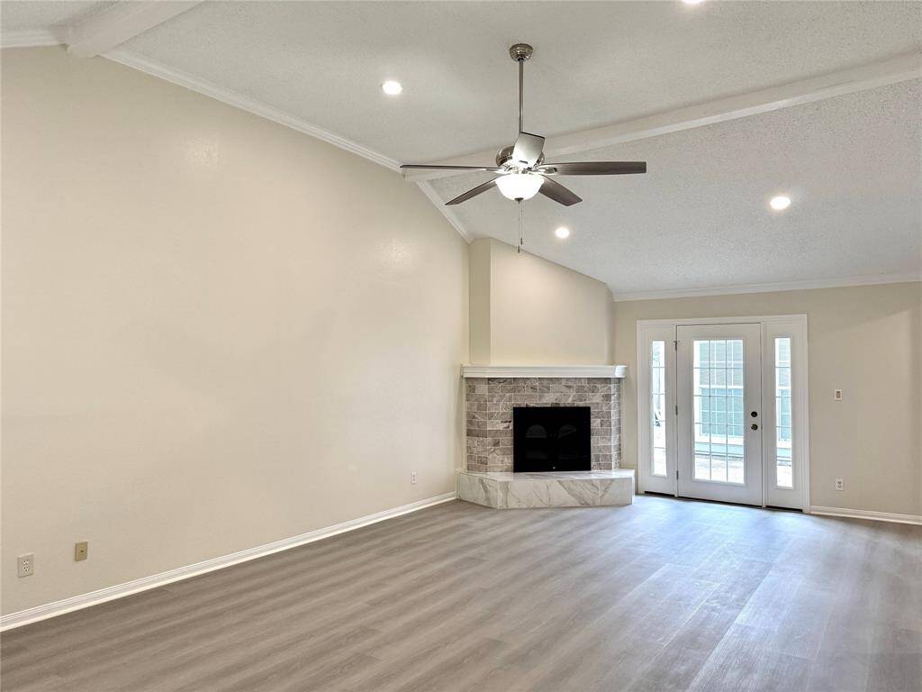 Welcome to 11127 Willwood, your future home showcasing a modern open-concept kitchen and living area. The kitchen features sleek stainless steel appliances, white Shaker-style cabinetry, quartz countertops, and a central island with a built-in cooktop—perfect for both everyday use and entertaining. Recessed lighting illuminates the space, which flows seamlessly into a spacious living area with luxury vinyl plank flooring and a welcoming atmosphere.