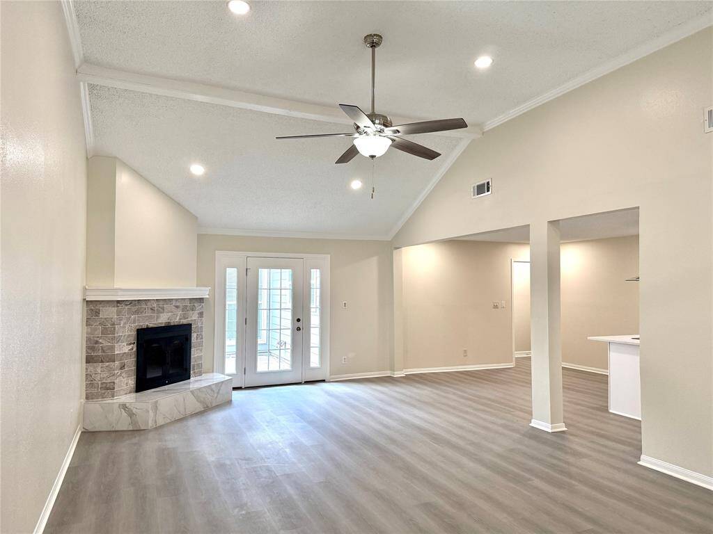Welcome to 11127 Willwood, your future home showcasing a modern open-concept kitchen and living area. The kitchen features sleek stainless steel appliances, white Shaker-style cabinetry, quartz countertops, and a central island with a built-in cooktop—perfect for both everyday use and entertaining. Recessed lighting illuminates the space, which flows seamlessly into a spacious living area with luxury vinyl plank flooring and a welcoming atmosphere.