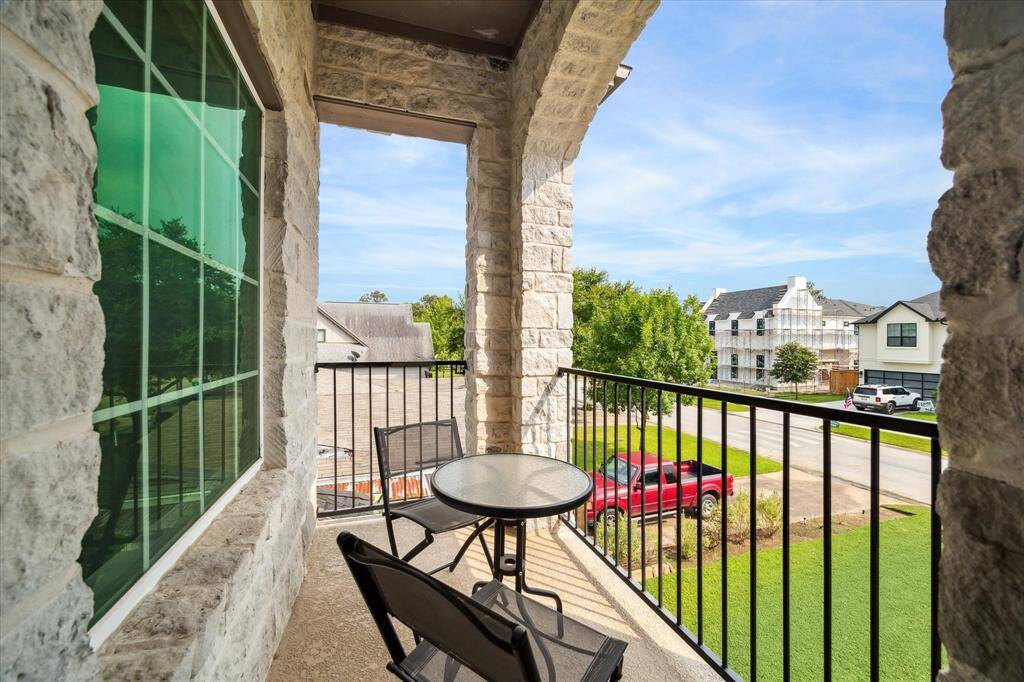 Accessible directly from an upstairs bedroom, this covered balcony offers a peaceful perch to enjoy fresh air and neighborhood views. Arched stone accents and wrought iron railing add architectural charm, while the covered design makes it a year-round retreat for quiet moments or casual seating.