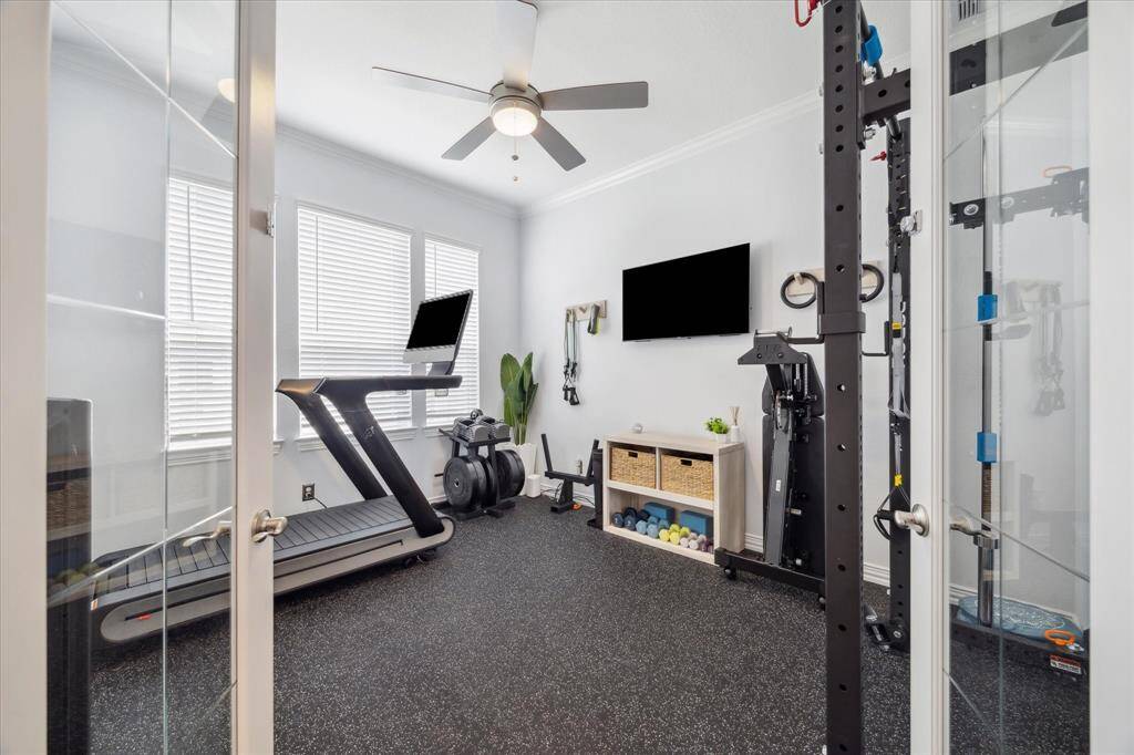 Glass French doors open to a private room currently outfitted as a home gym, complete with rubber flooring, ceiling fan, and abundant natural light. Whether used as a fitness space, office, or hobby room, this flexible area adapts easily to suit your lifestyle needs.