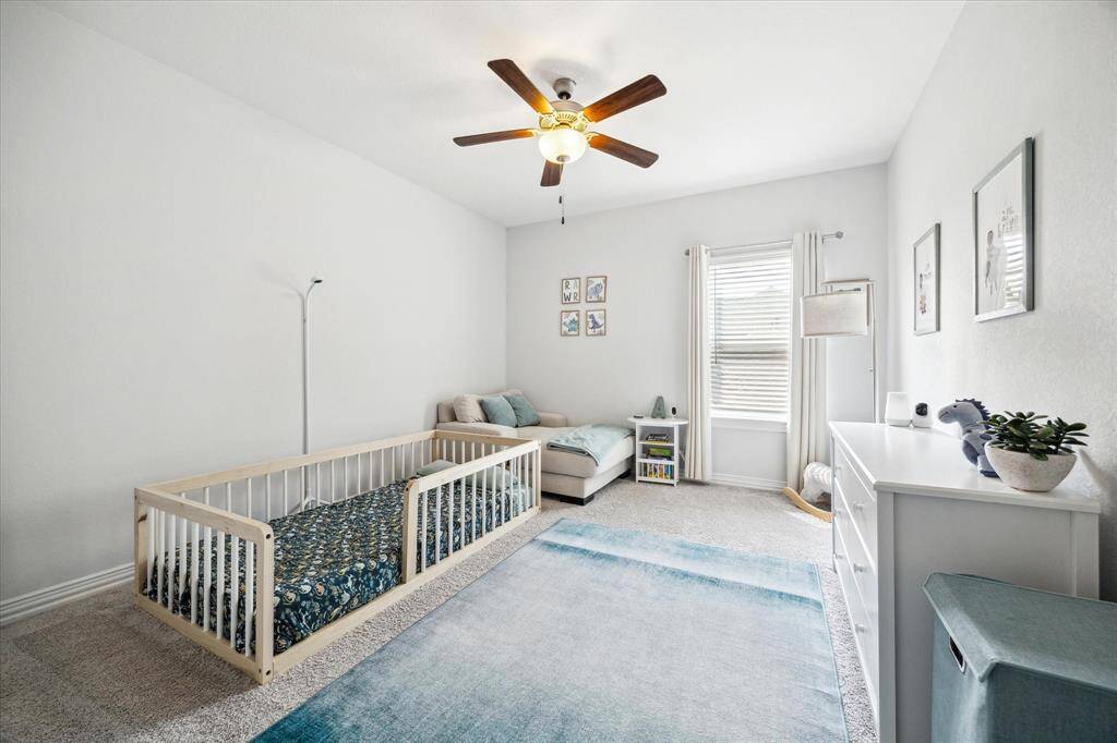 Bright and roomy, this secondary bedroom offers ample space for both sleep and play. A large footprint and soft neutral finishes make it easy to adapt as children grow, while natural light from the window and a ceiling fan overhead keep the space airy and comfortable. Whether styled as a playroom, nursery, or guest retreat, the layout allows for flexibility over time.