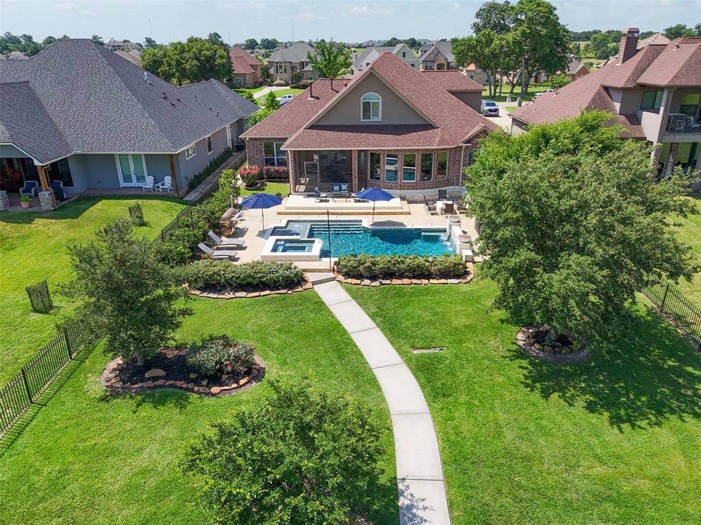 A stunning aerial view that shows off the backyard, lush landscaping with mature trees offering plenty of privacy, and all the space you need to relax or entertain.