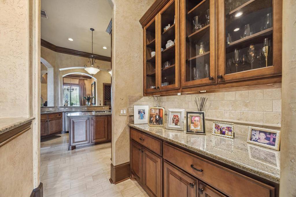 Butler pantry and dry serving bar located between the kitchen and formal dining room. Glass cabinets for crystal and china storage.