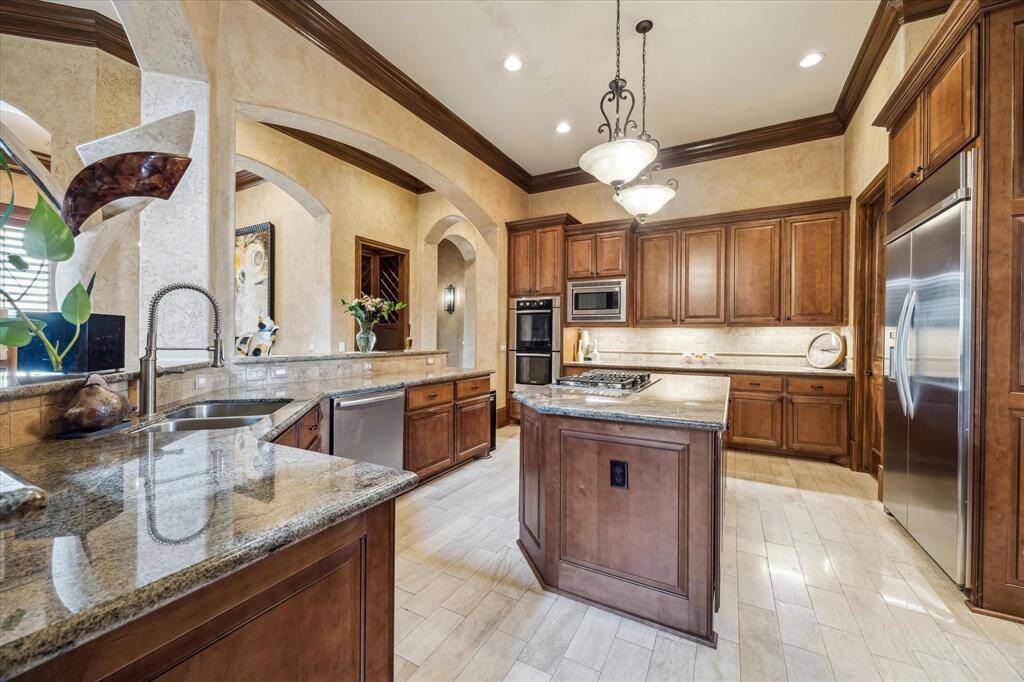 Spacious gourmet kitchen with stained cabinetry, stainless steel appliances, skip trowel faux finished walls, granite countertops and plenty of prep space.