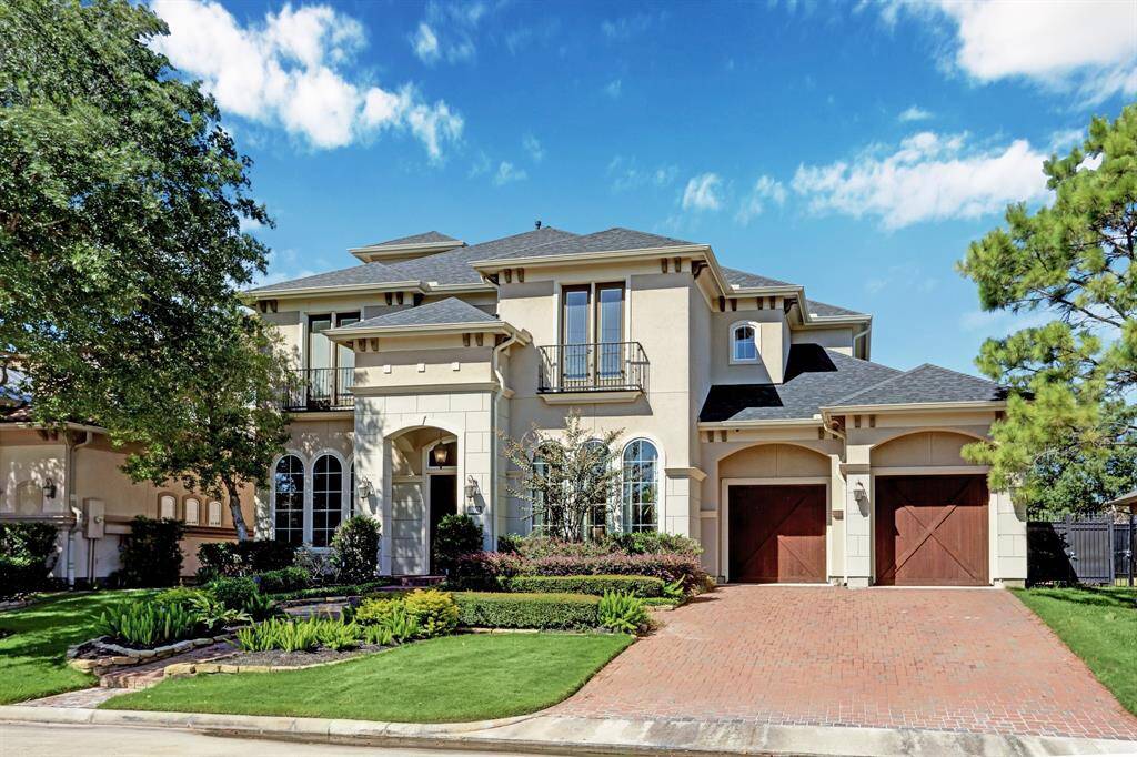 Front exterior with stucco, cedar garage doors, lush landscaping, 3 car garage , and golf course view of Hole #15 in the gated community of Royal Oaks Country Club.