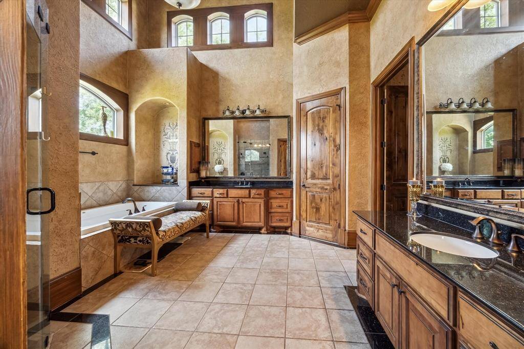 Two story primary bathroom suite with soaking tub, separate walk in shower, and separate vanities with ample storage.