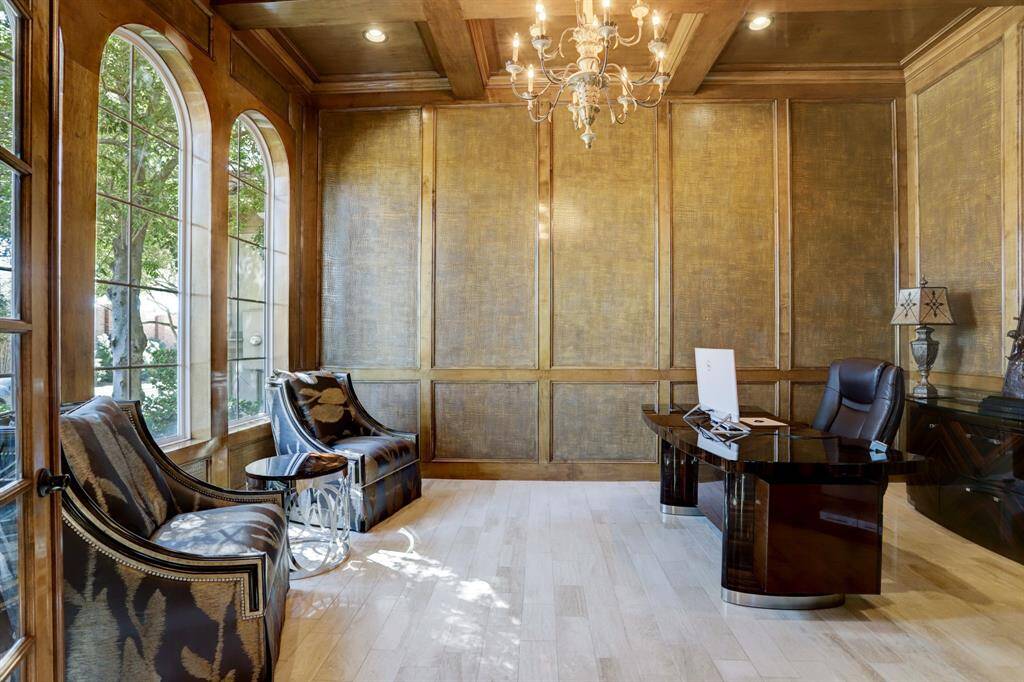 Spacious study with custom finished paneling, chandelier, and beautiful arched windows.