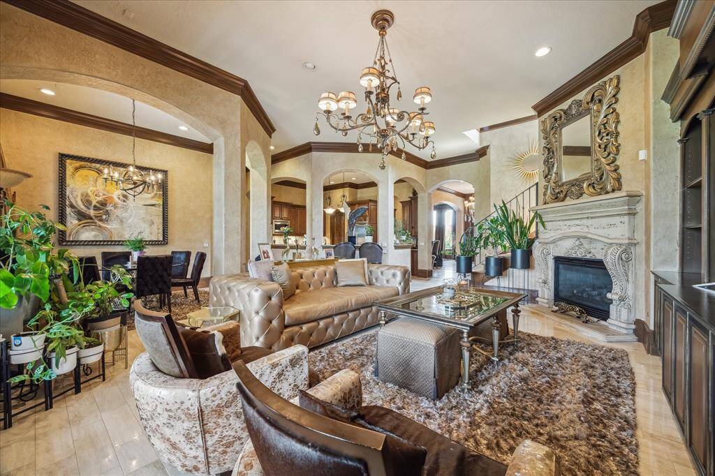Family Room with cast stone fireplace surround, custom built ins, chandelier, stained crown moulding and baseboards, and open access to the covered lanai, breakfast room and kitchen.