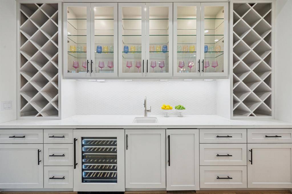 Fabulous Wet-Bar with a JennAir Panel Ready Ice Maker, JennAir 24" Wide Panel Ready Wine Cooler,  Slab Quartz Counter, 1.5 Hex Mosaic Glossy Tile Backsplash, Undermount Bar Sink with Single Lever Pull-DownFaucet, and Under-Cabinet Lighting. Glass Fronted Cabinet Doors with Glass Shelving and lighting to display Glasses and Barware. There is also two towers of built-in wine Storage flanking each end of the bar.