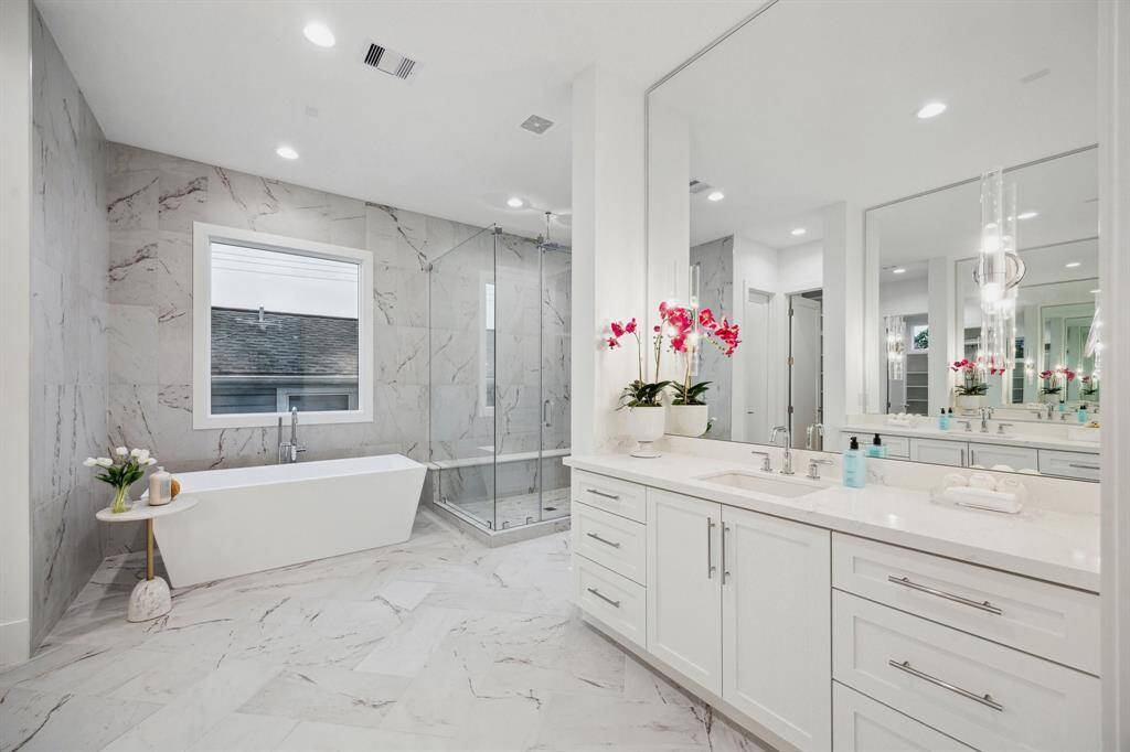 A closer look at the dual counters with Rectangle Under-Mount Sinks,  Widespread Bathroom Sink finished in Chrome. There are frameless Mirrors with Two "Vaxcel Lighting" 2 Bulb Sconces with clear glass shades in Polished Nickel on Each Vanity.