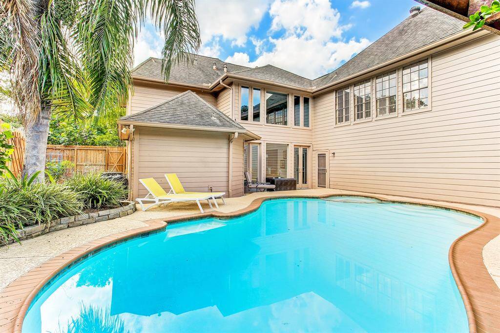 Large pool with lots of shade in afternoons surrounded by beautiful landscaping and palm tree.
