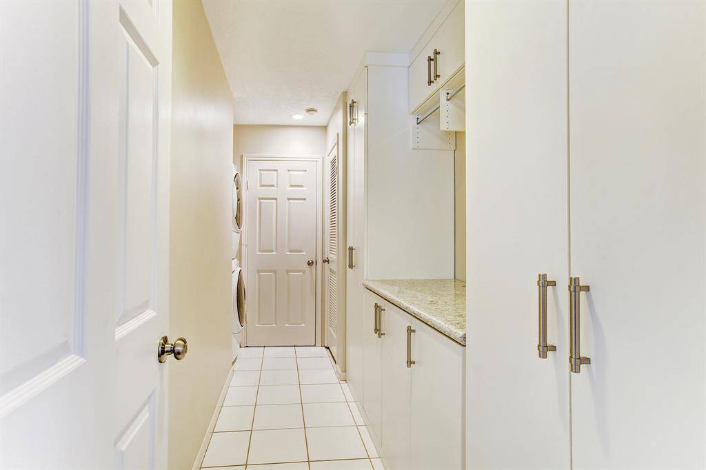 Upstairs laundry with folding table and plenty of hanging space with built-ins and silestone counter tops designed by Spaceman Closets.