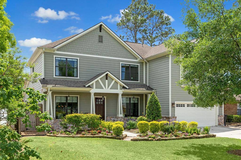 This charming two-story home features a modern exterior with white trim, a welcoming front porch, and a spacious two-car garage.