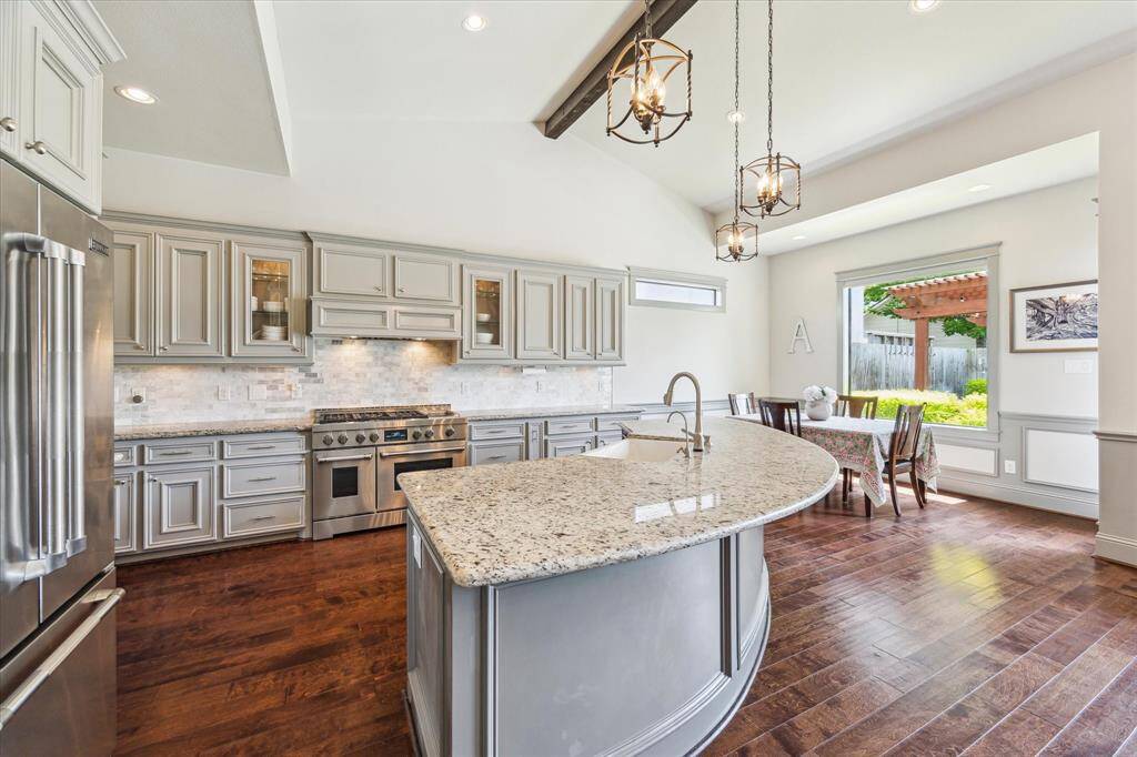 View of kitchen with glass front cabinets flanking the 48 inch Jenn-Air gas range with chrome infused griddle