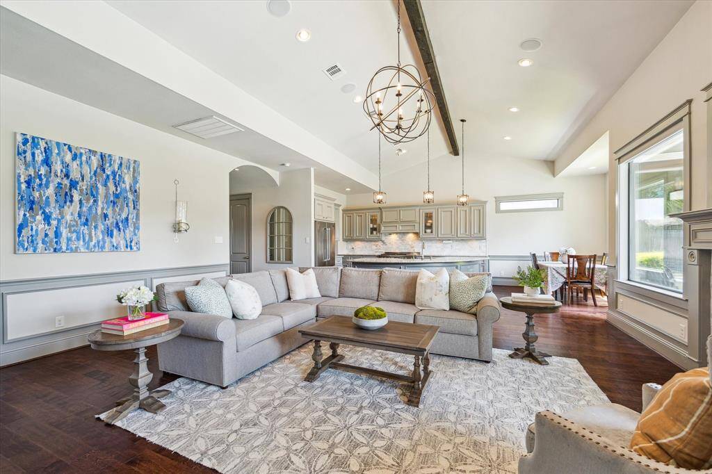 Large family room with soaring ceilings and beam accent. Double sided gas fireplace shared with outdoor covered patio