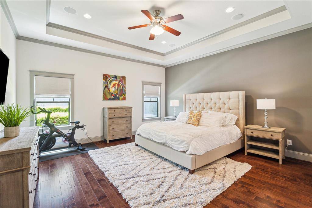 Large primary suite overlooks the backyard with hardwood floors, and high coffered ceiling