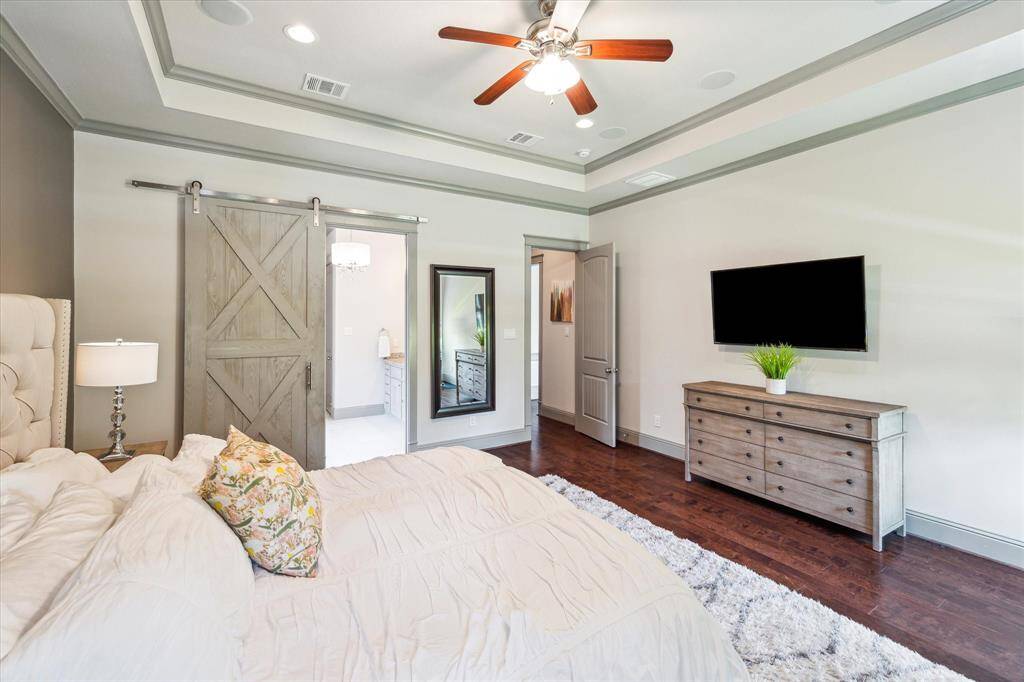 View of primary bedroom with custom barn door leading to bathroom