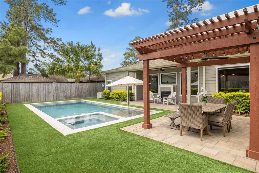 Pergola with outdoor fan overlooks the manicured backyard