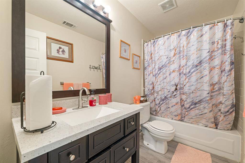 The secondary bathroom features light countertops, a large mirror, and ample space—perfect for accommodating guests or family.
