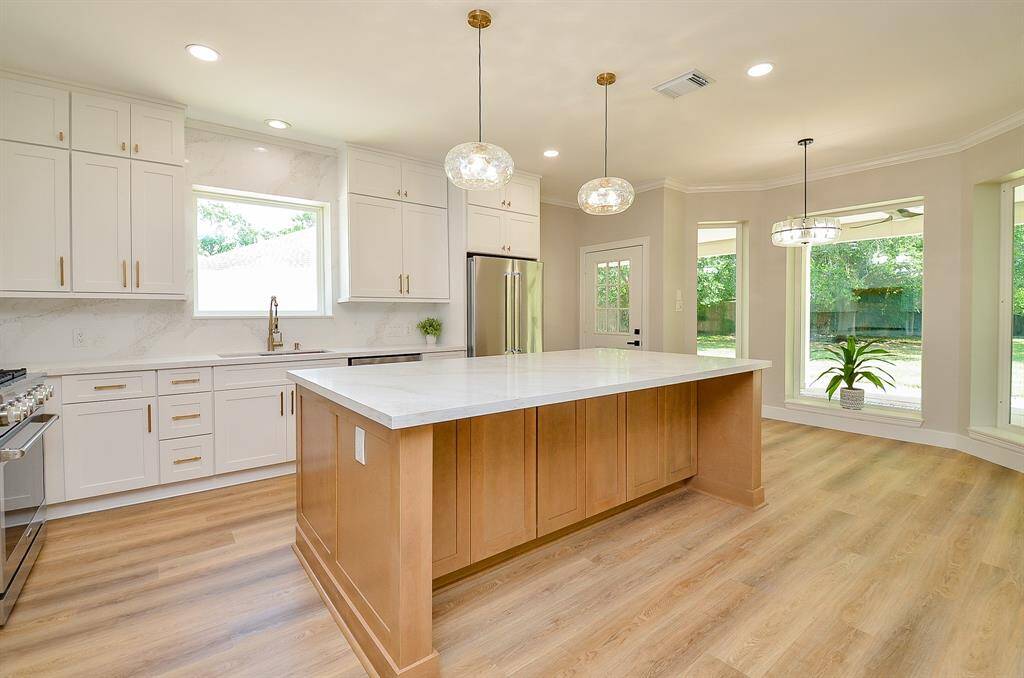 Designer lighting with lovely accent pieces enhances the elegant space of this high-end kitchen.