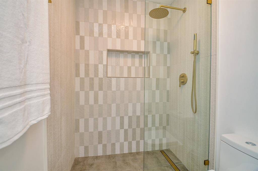 Luxury bathroom shower with tiled floor to ceiling with inset floor drain in a gold finish