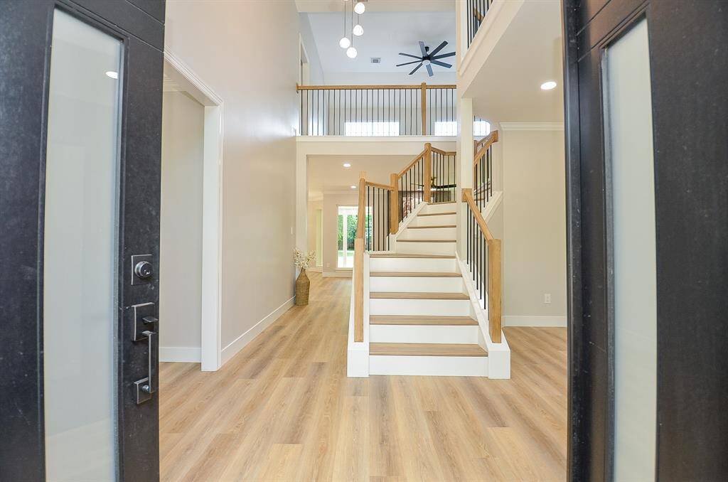 This inviting entryway features luxury flooring leading to a staircase with elegant iron railings.
