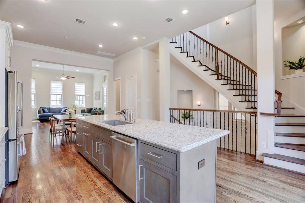 View of all the softclose shaker style cabinets and softclose drawers. Pretty brushed nickel hardware on cabinets. Notice the electric plugs on side of the island. View of staircase leading to 3rd floor.