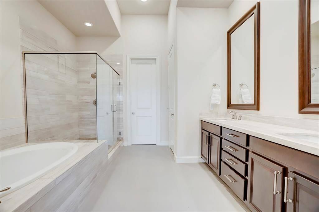 Spa like primary bathroom feels like a top notch retreat with dual sinks, glass shower, oversized soaking tub and separate toilet.