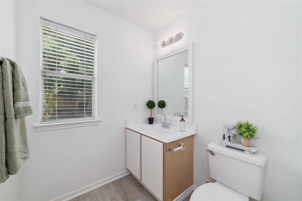 Bright and modern bathroom with a large mirror, sleek vanity, and natural light from a window.