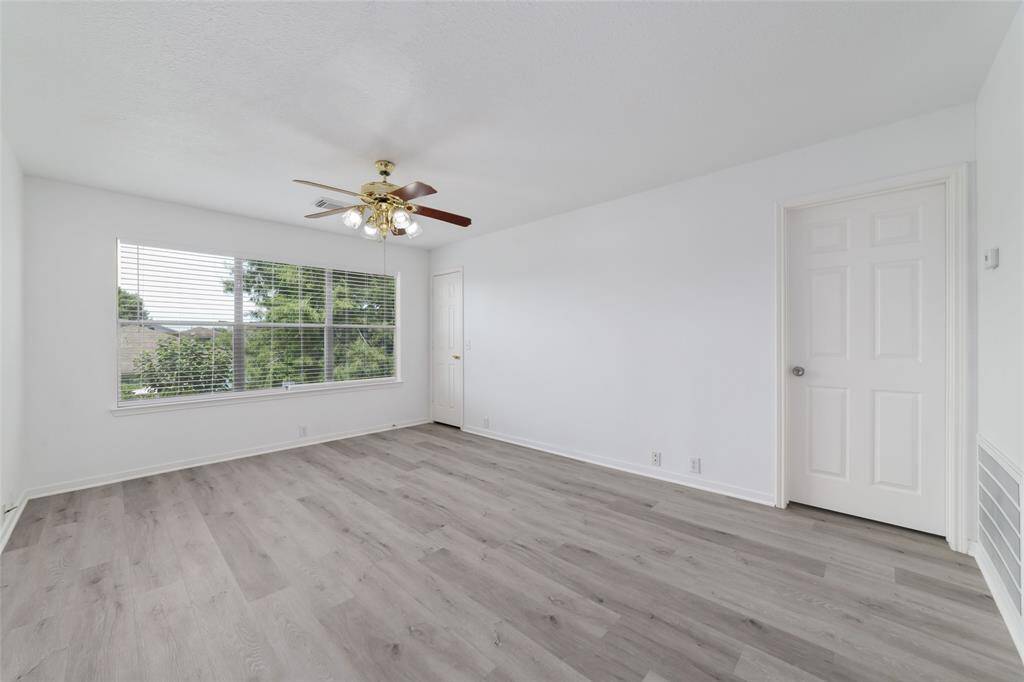 Bright, spacious game room with fresh white walls and sleek laminate flooring.