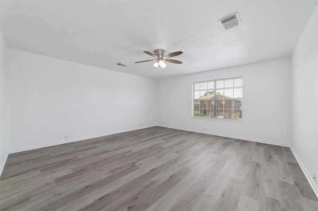 Spacious primary bedroom bright room white walls, a ceiling fan, and a large window offering ample natural light.