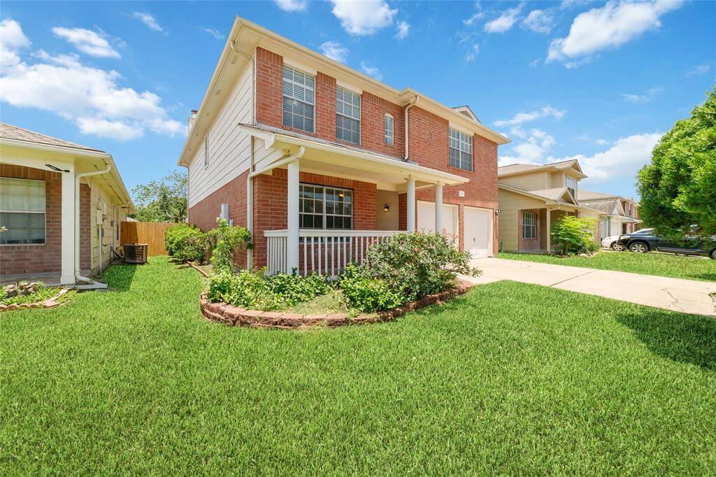 This charming two-story home features a brick exterior with a welcoming front porch, and a spacious driveway leading to a two-car garage. Perfect for family living.