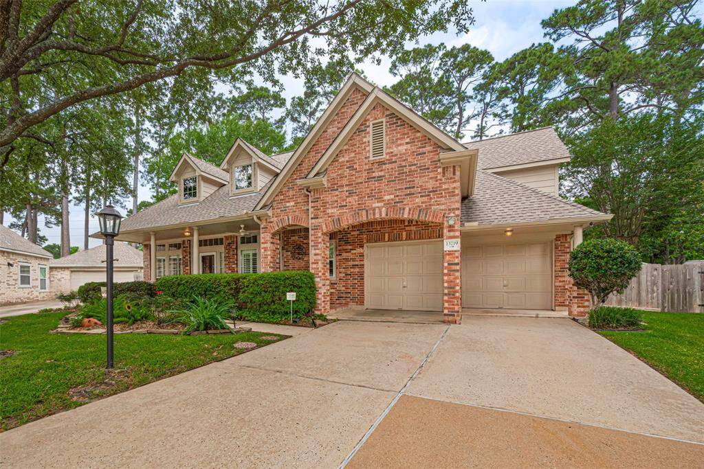 Two-car oversized garage with extended cover and storage nook, double-wide driveway and mature trees.