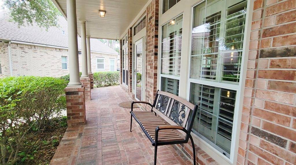 Welcome guests on the inviting front porch featuring elegant brick flooring, pillars and a beautiful palm leaf design ceiling fan.
