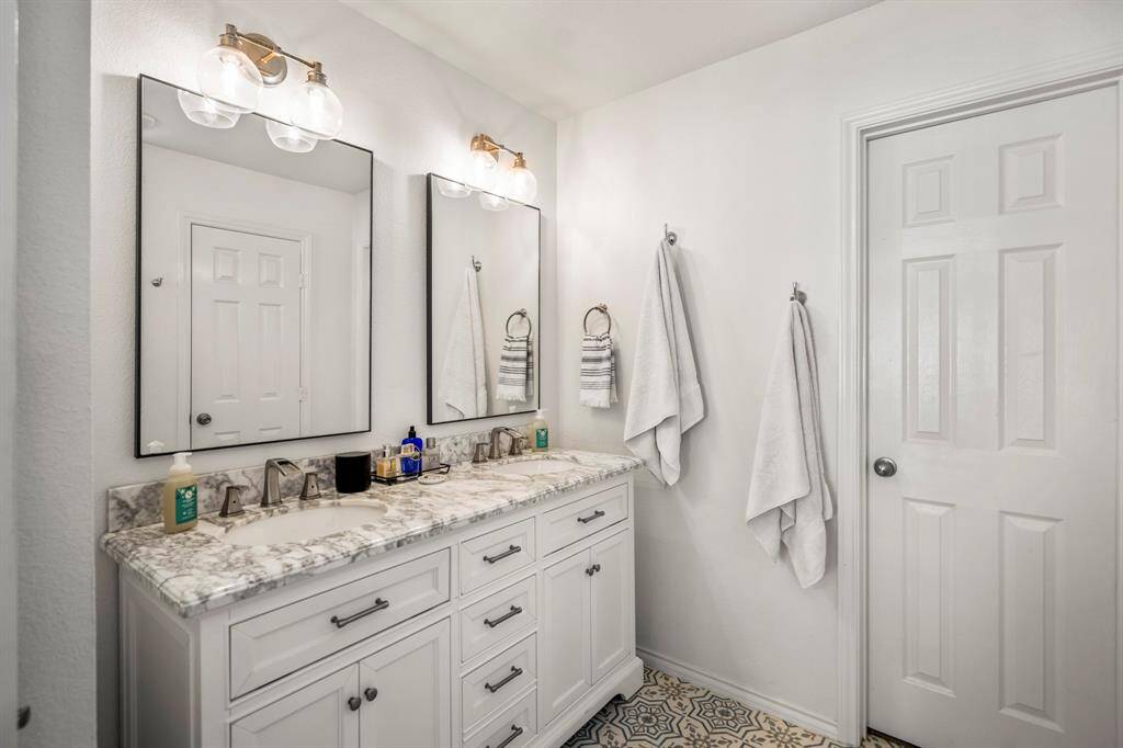 Dual marble vanities and a thoughtfully designed layout add convenience and elegance to your morning routine in this bright, polished ensuite bath.