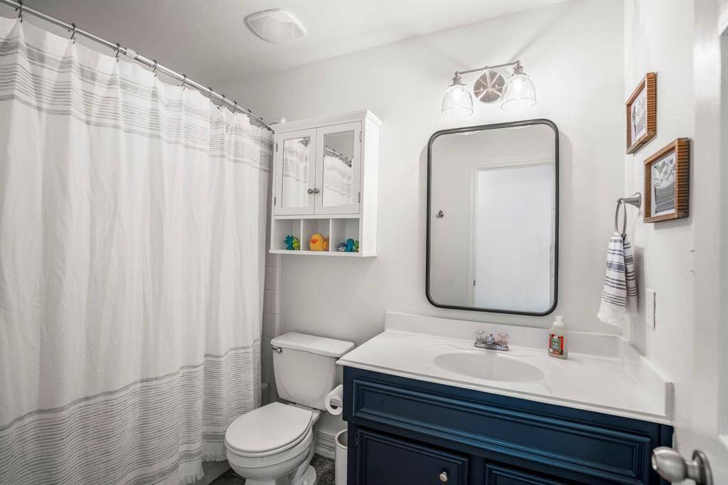 A full guest bathroom offers updated finishes and a stylish navy vanity, making a statement while serving everyday needs with ease.