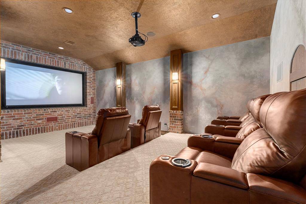 Incredible media room is privately located off of the garage area. A built-in snack bar complete with lighted checking, surround sound, built-in projector and scree, and sconces lighting make this the perfect setting for watching the latest flicks.