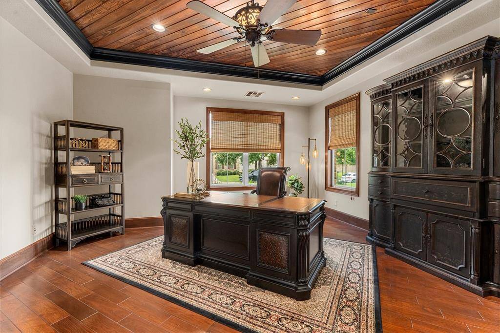 Custom double glass arched pocket french doors open to this handsome home office with clapboard wood ceiling