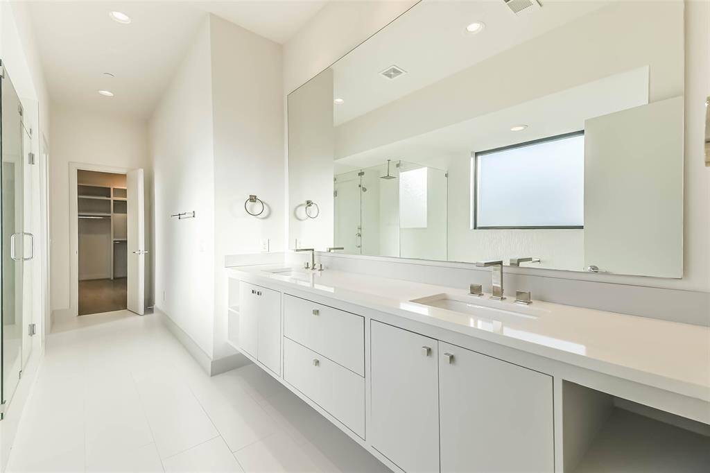 Double sinks and vanity space round out the spacious bath with one of two walk-in primary closets visible at the back of the space.