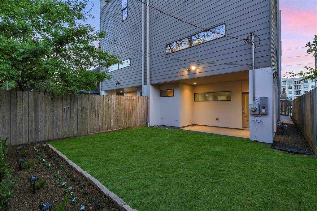 Another view of the zen-like backyard showcasing the exterior lighting, mature trees and access to the walkway that leads to the front door and gate.