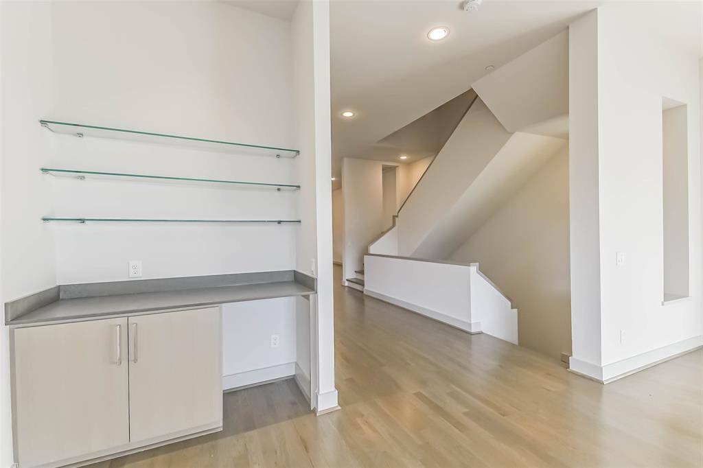 Dry bar is conveniently located between living room and dining area.  Glass shelving, silestone countertop, storage and space for a beverage/wine refrigerator.