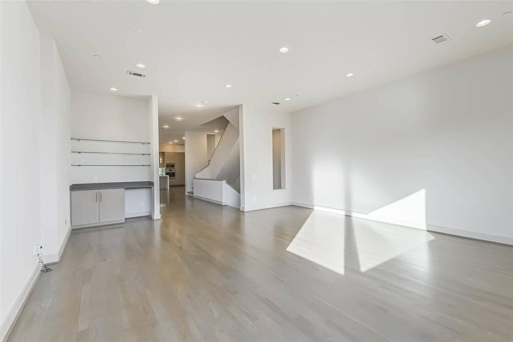 View of the family room looking towards the dining room, kitchen and additional living space.  The white oak floors, recessed lighting and fresh paint throughout make the home easy to enjoy.