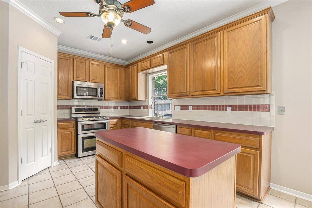 Large kitchen with an island and ceiling fan. Double doors lead to walk in pantry. Recent stove and microwave!