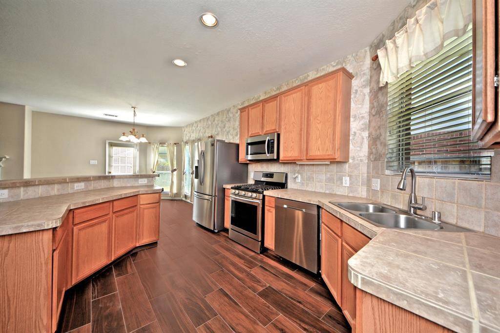 The gourmet kitchen is equipped with a swan pull-out faucet, built-in stainless steel microwave, and a new 5-burner gas range—designed for function and style.
