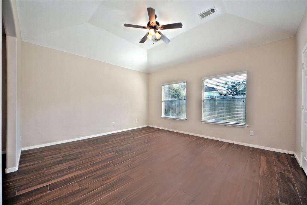 The primary suite is tucked away from the main living areas and guest bedrooms, offering added privacy, high ceilings, and a peaceful retreat. An arched doorway leads into a versatile bonus space.