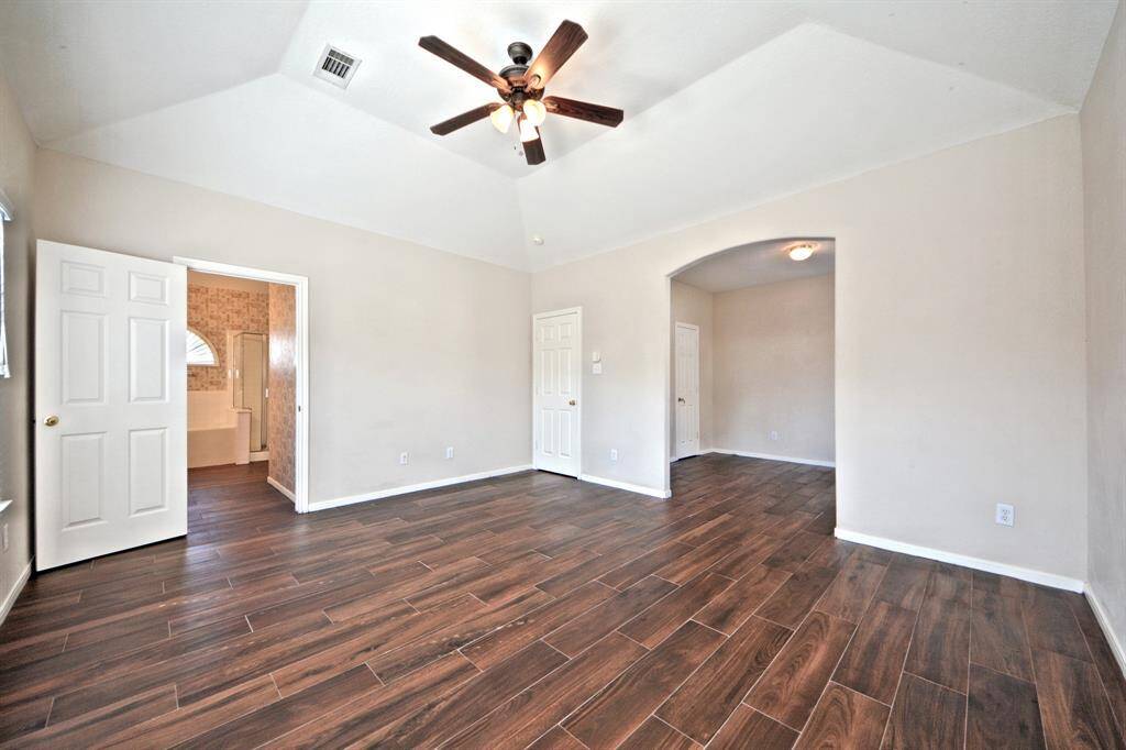 Connected to the bonus room, the spacious primary suite offers high ceilings, a ceiling fan, and direct access to the luxurious en suite bathroom.
