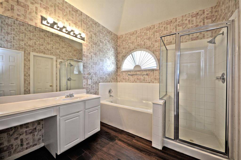 This luxurious primary bathroom features a deep garden tub, a walk-in shower, dual vanities, and access to two large walk-in closets—designed for both comfort and convenience.