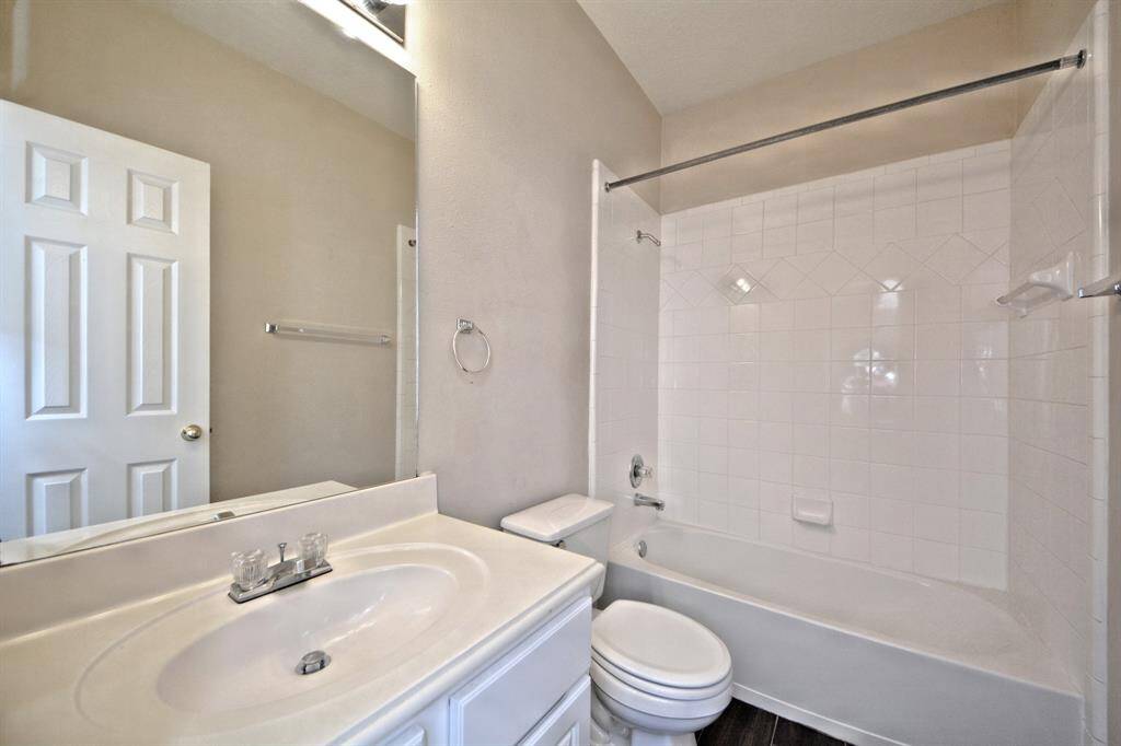 The guest bathroom includes a tub and shower combination with a large vanity and clean, neutral finishes for everyday ease.
