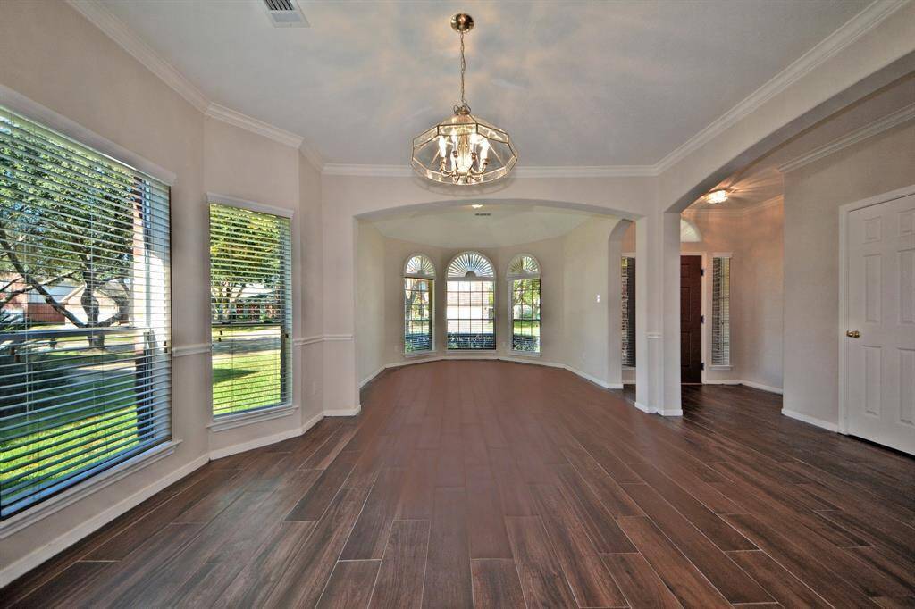 The formal living room features a wall of windows that fills the space with natural light, complemented by beautiful tile wood flooring and an open, airy layout.